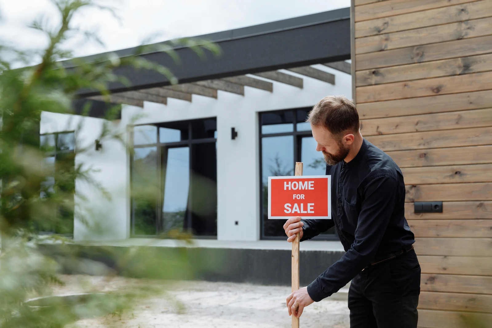 Real estate agent placing a sale sign outside a modern home
